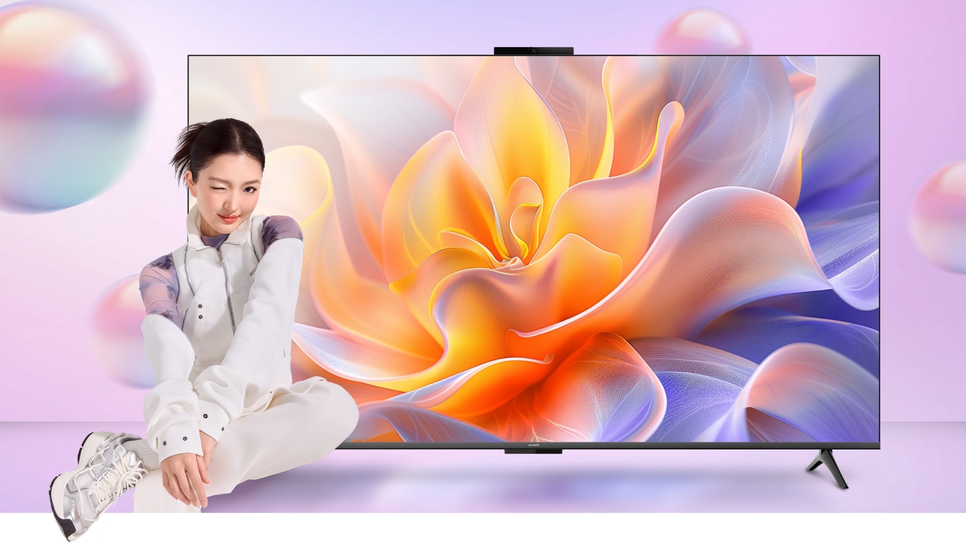 用户坐在华为 Vision 智慧屏 5 SE 的旁边,展示了智慧屏的时尚设计